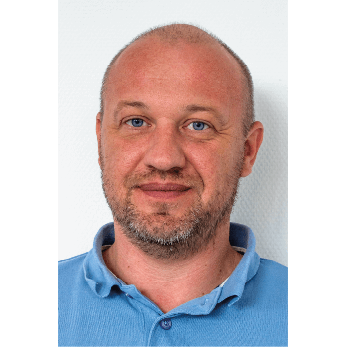 Ein Mann prüft konzentriert Baupläne an einem Tisch. Im Hintergrund: eine ruhige, helle Werkstatt ohne Ablenkung.